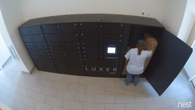 Footage from a wall-mounted security camera shows a woman picking up a package from the shared Luxer Oversized Locker. 